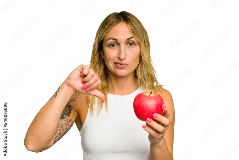 Young caucasian woman holding an apple isolated on green chroma background showing a dislike gesture, thumbs down. Disagreement concept. Young caucasian woman holding an apple isolated on green chroma background showing a dislike gesture, thumbs down. Disagreement concept.