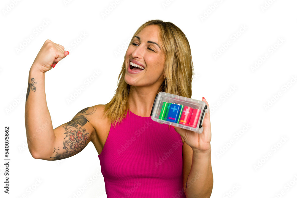 Obraz premium Young caucasian woman holding battery box isolated on green chroma background raising fist after a victory, winner concept.