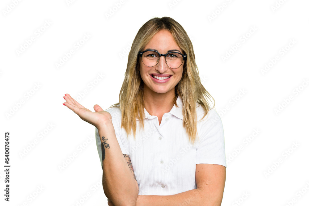 Obraz premium Young caucasian woman isolated on green chroma background showing a copy space on a palm and holding another hand on waist.