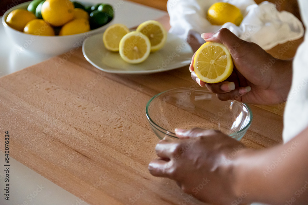African American woman hands holding half cut lemon cross section above glass bowl. Copy Space African American woman hands holding half cut lemon cross section above glass bowl. Copy Space