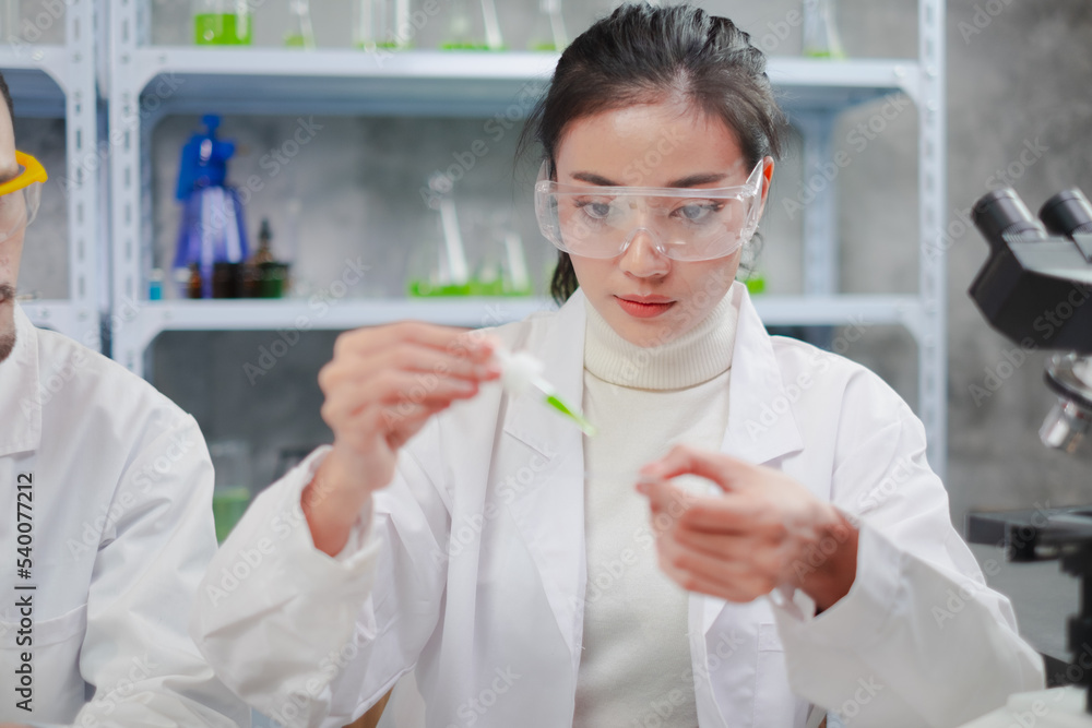 Asian Female Scientist is consentrate or focusing while drop down green substance. Concept of laboratory eco or natural cosmetic, medicine, organic skin care. Concept of Eco experiment. Focus on face. Asian Female Scientist is consentrate or focusing while drop down green substance. Concept of laboratory eco or natural cosmetic, medicine, organic skin care. Concept of Eco experiment. Focus on face.