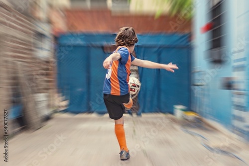 Niño de espaldas pateando una pelota de futbol