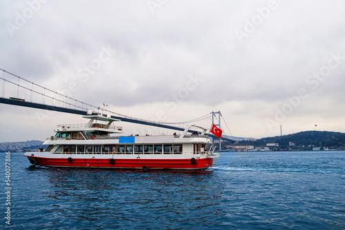 A passenger ferry passing under the Istanbul Bosphorus Bridge.