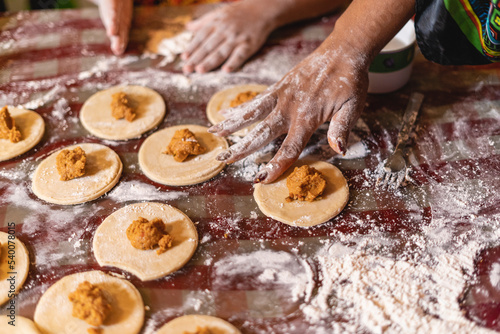 Imagen horizontal de las manos de una madre y su hija preparando algunos bocadillos caribeños juntas en su casa. 
