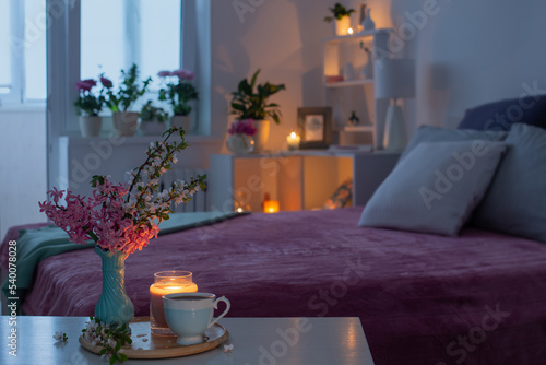 cozy bedroom in  evening with flowers and tea