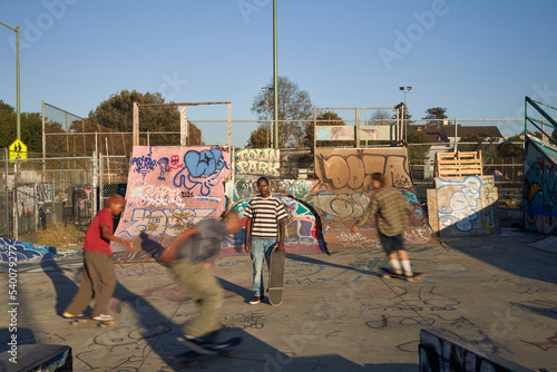 Four young skateboarders in skatepark skateboarding
