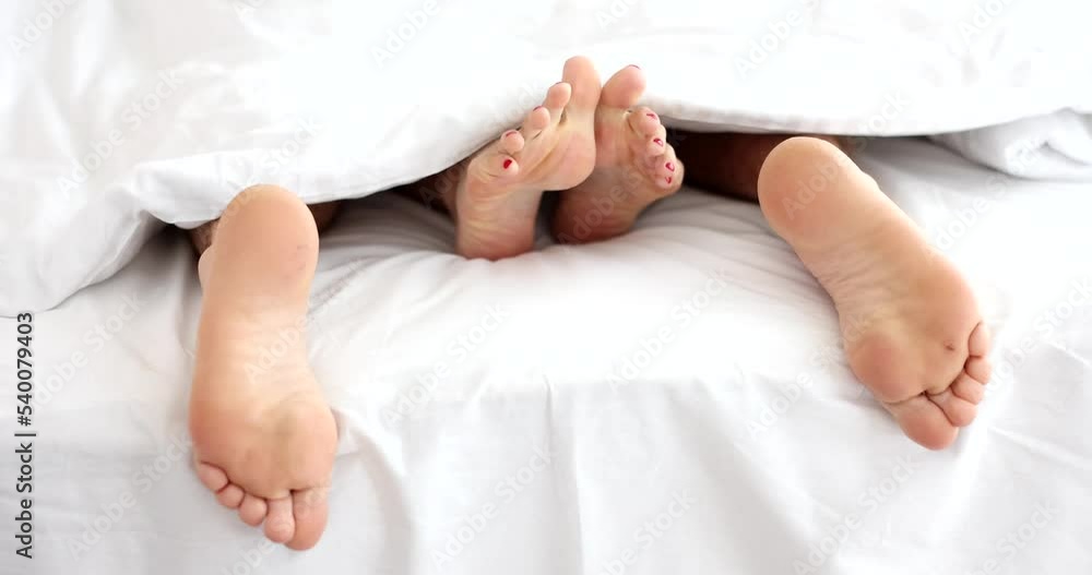 Male and female feet lying under covers in bed closeup 4k movie slow motion Male and female feet lying under covers in bed closeup 4k movie slow motion