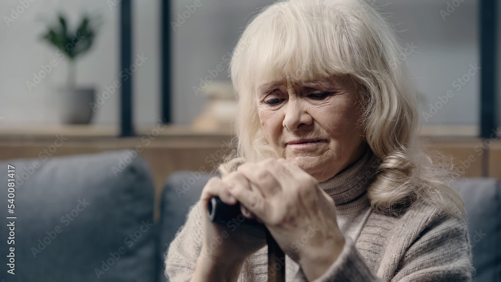 depressed senior woman with dementia sitting with walking cane at home. depressed senior woman with dementia sitting with walking cane at home.