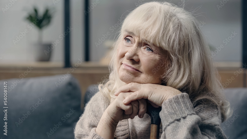 pensive senior woman with dementia sitting with walking cane at home. pensive senior woman with dementia sitting with walking cane at home.