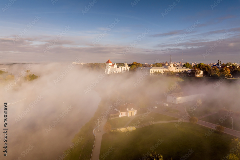 Fototapeta premium earlier foggy morning and aerial panoramic view on medieval castle and promenade overlooking the old city and historic buildings near wide river
