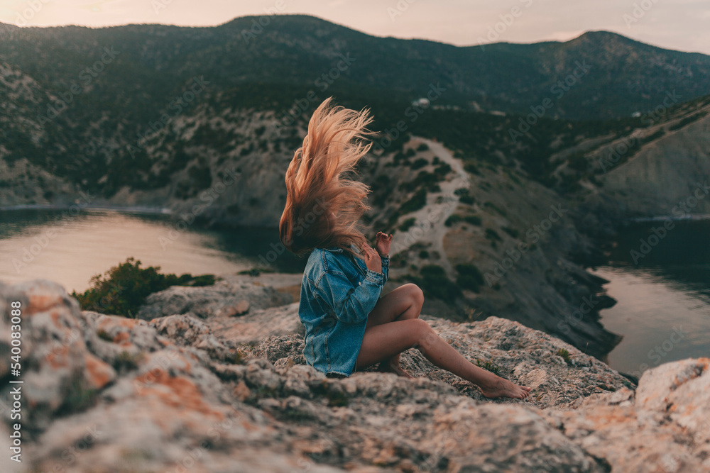 young woman with long blond hair enjoys the mountain scenery