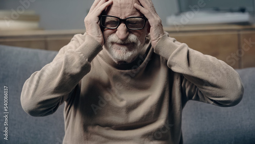 bearded senior man with dementia suffering from headache and touching head. © LIGHTFIELD STUDIOS
