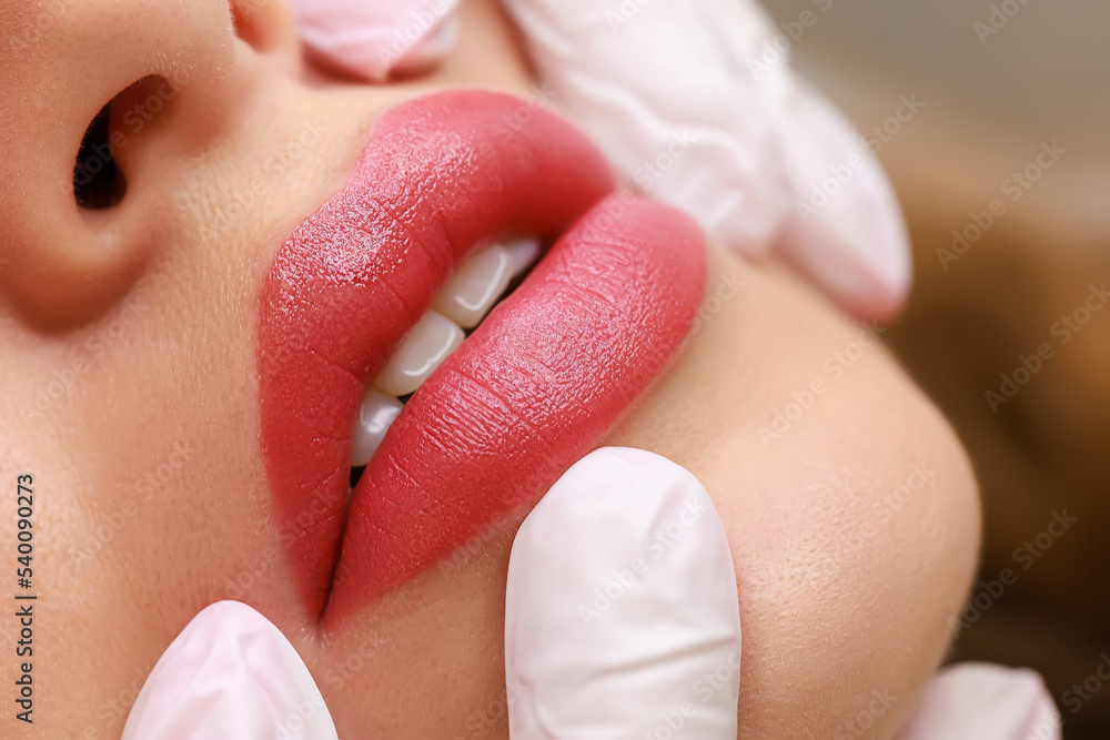 close-up of sexy lips of young models on which permanent lip makeup is  performed, the master stretches the tips of the model's lips with his  fingers Photos | Adobe Stock