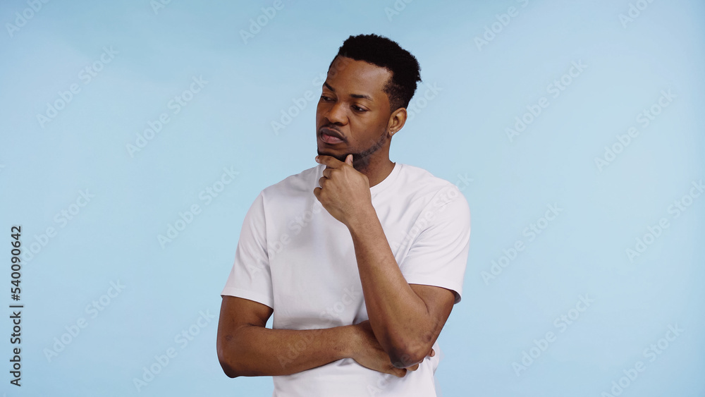 pensive african american man in white t-shirt looking away isolated on blue. pensive african american man in white t-shirt looking away isolated on blue.