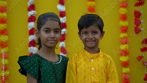 Portrait of happy indian young kids or bothers and sister wearing traditional cloths having fun or celebrating festival like diwali or rakshabandhan. photo