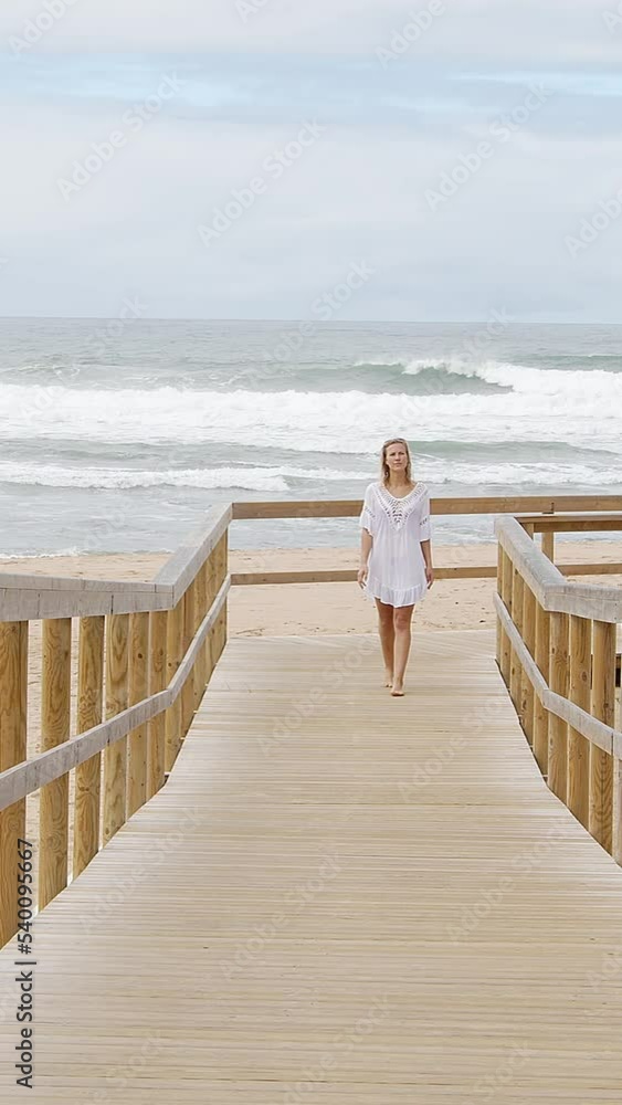 Cute girl walks on a wooden pier at the beach - travel photography Cute girl walks on a wooden pier at the beach - travel photography
