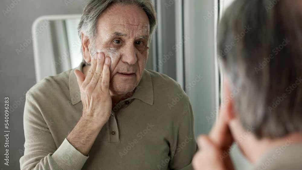 Old man applying cream to his face Old man applying cream to his face