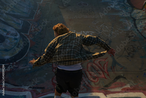 Portrait of young non-binary skating on skateboard at skatepark
