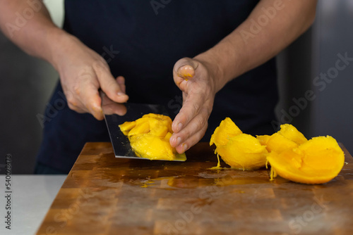 Chef cook cutting fresh mango for fruit salad on wooden cut board