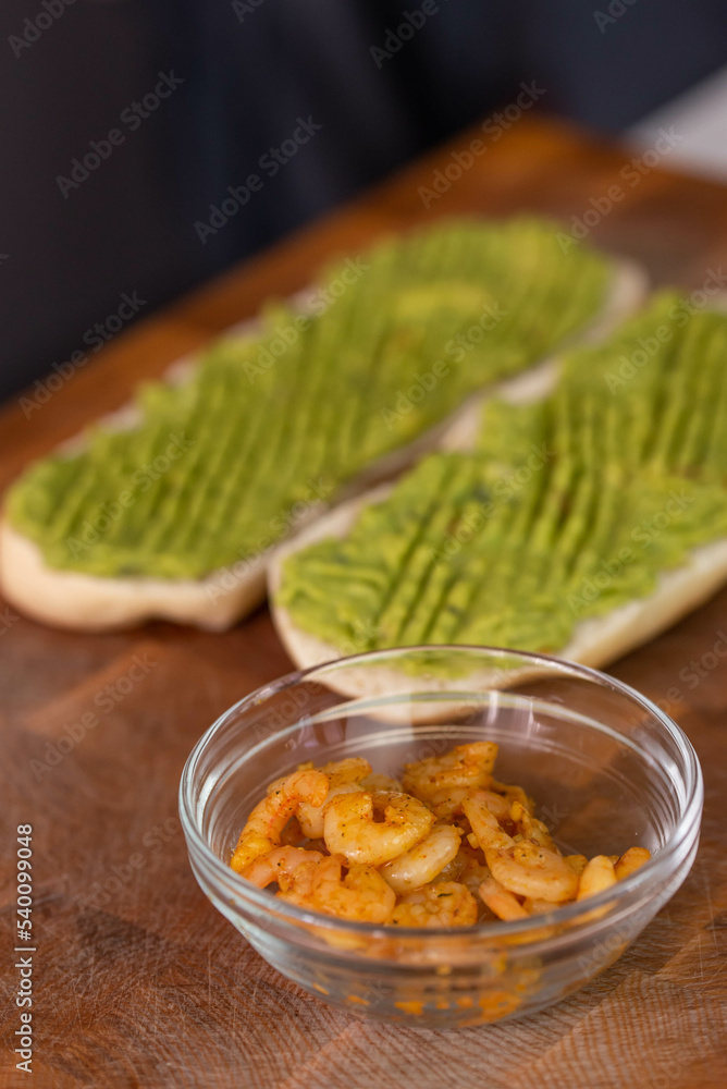 Chef cook hands making fresh diet avocado toast with seafood shrimps. Healthy vitamin breakfast.