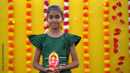 Cute Indian little girl holding lord ganesha sclupture in hand and celebrate diwali festival. photo