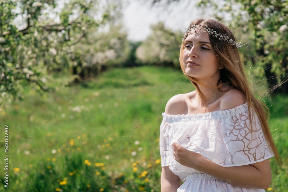 A beautiful pregnant girl in a white dress walks in an apple orchard on a sunny spring day. High quality photo A beautiful pregnant girl in a white dress walks in an apple orchard on a sunny spring day. High quality photo