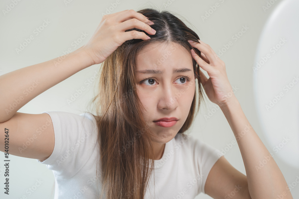 Fototapeta premium Hair loss problem, Asian woman look at scalp worry about balding.