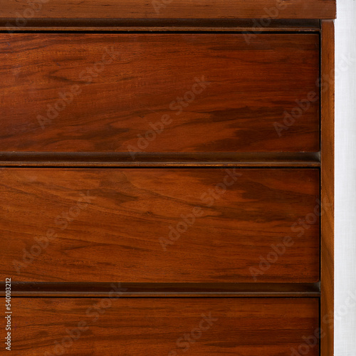Front detail of vintage walnut, mid-century modern dresser. Wood grain texture.