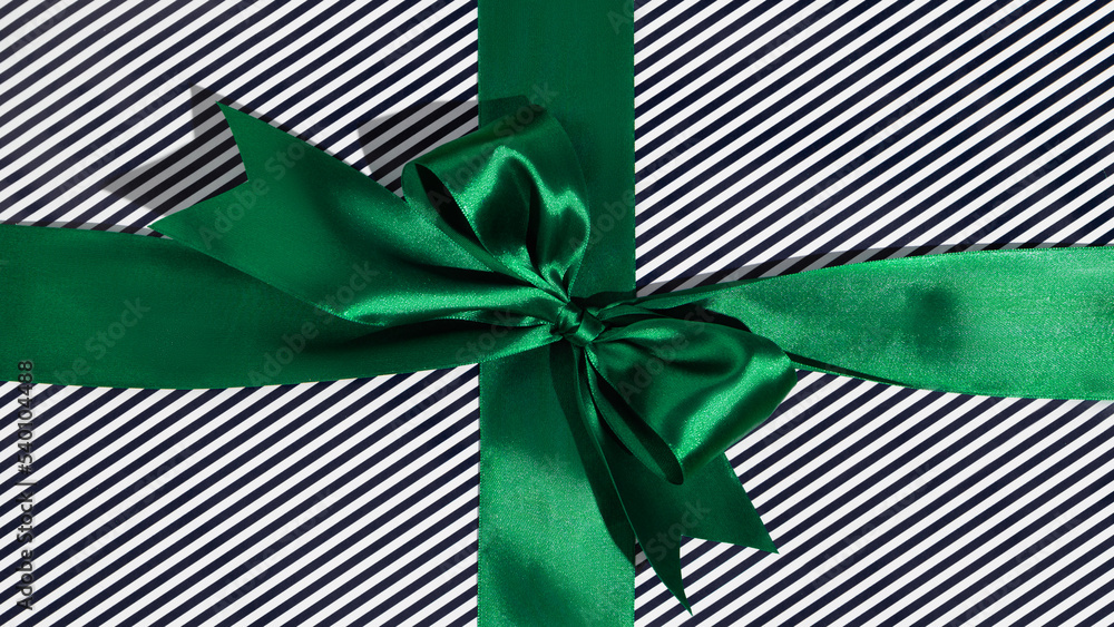 Fototapeta premium Green gift ribbon and bow on black and white wrapping paper