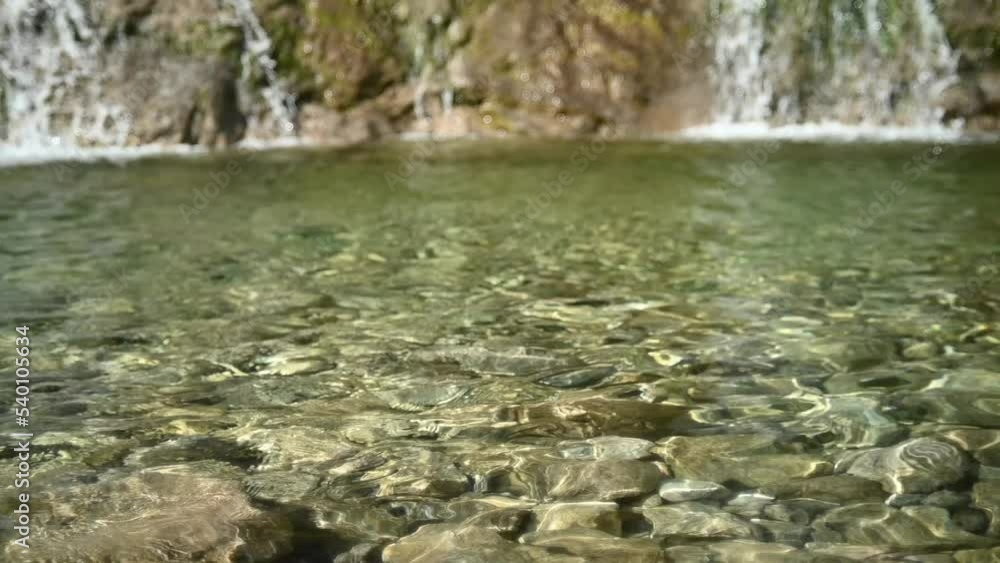 Waves and sunlight effects in the pool created by a waterfall (slow motion, bokeh) Waves and sunlight effects in the pool created by a waterfall (slow motion, bokeh)