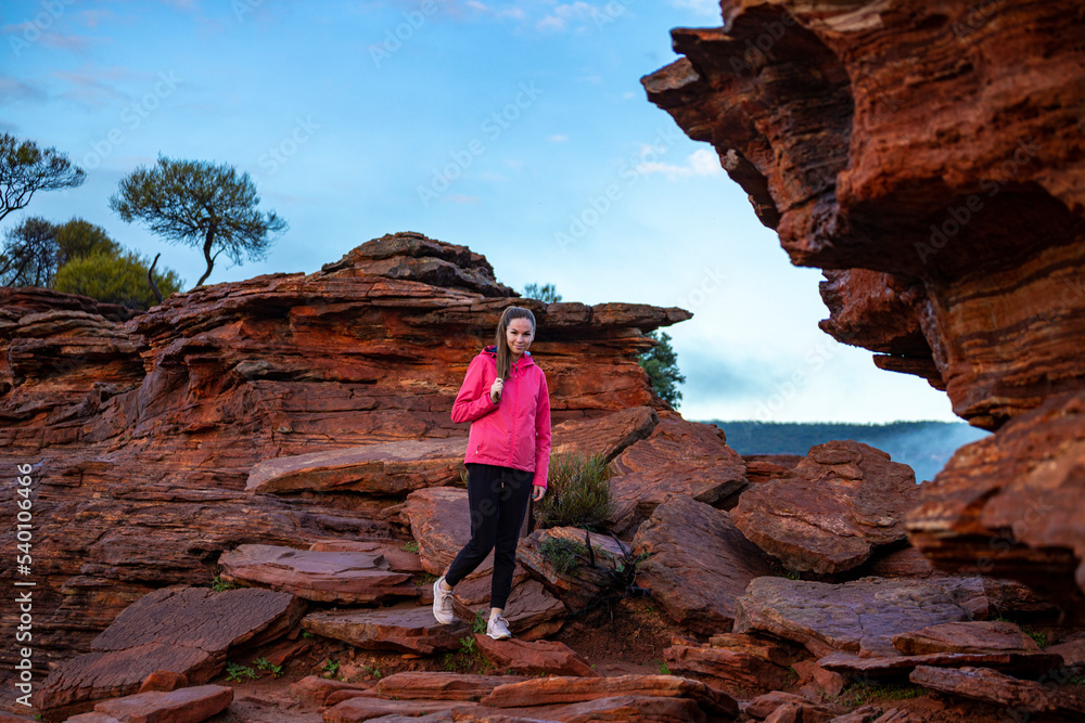 long-haired girl walks along a ridge on the red rocks of kalbarri national park in western australia; hiking in the wilderness, australian outback