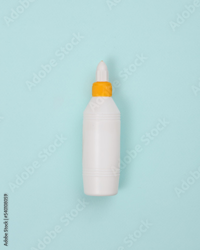 Glue bottle on a blue background. Minimalist photo. Top view