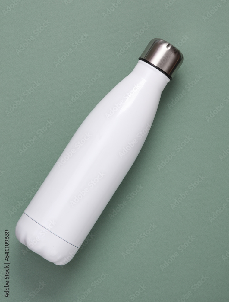 White metal thermal bottle for water on green background. Stainless Steel Vacuum Insulated thermos Bottle White metal thermal bottle for water on green background. Stainless Steel Vacuum Insulated thermos Bottle