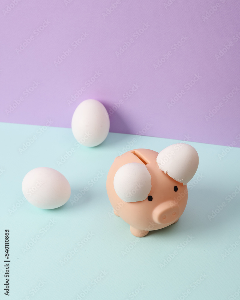 Creative layout. Piggy bank with eggshell on two tone pastel background. Conceptual pop. Minimal business still life. Creative layout. Piggy bank with eggshell on two tone pastel background. Conceptual pop. Minimal business still life.