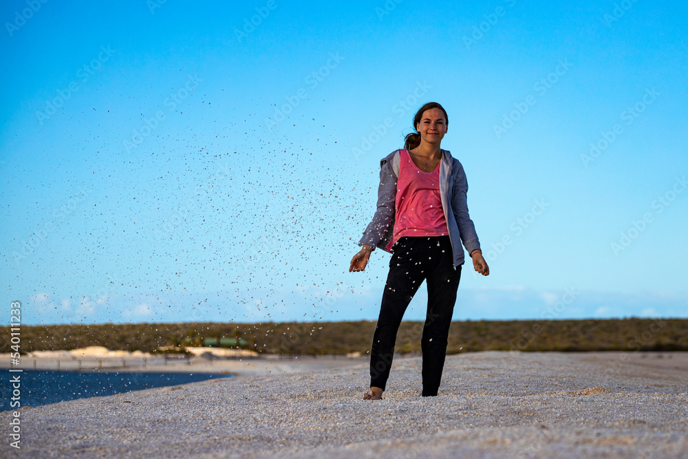 A beautiful girl plays with seashells on the famous shell beach in western australia, sunset on shell beach in francois peron national park A beautiful girl plays with seashells on the famous shell beach in western australia, sunset on shell beach in francois peron national park