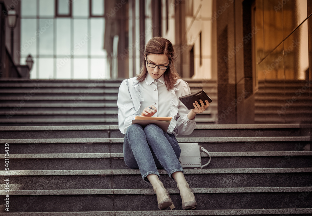 Modern business woman writes down important information while walking on the stairs Modern business woman writes down important information while walking on the stairs