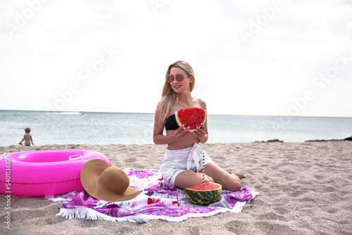 Beautiful blond woman have sunbathing in the beach. Young girl wearing swimsuit, sunglasses