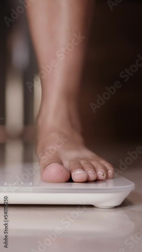 Woman on scales measure weight. Female dieting checking BMI weight loss. Vertical video.