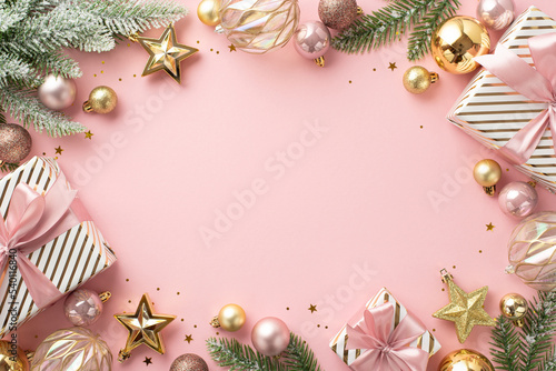 Fototapeta Naklejka Na Ścianę i Meble -  Christmas concept. Top view photo of present boxes fir branches in snow decorated with stylish baubles star ornaments and confetti on isolated light pink background with blank space in the middle