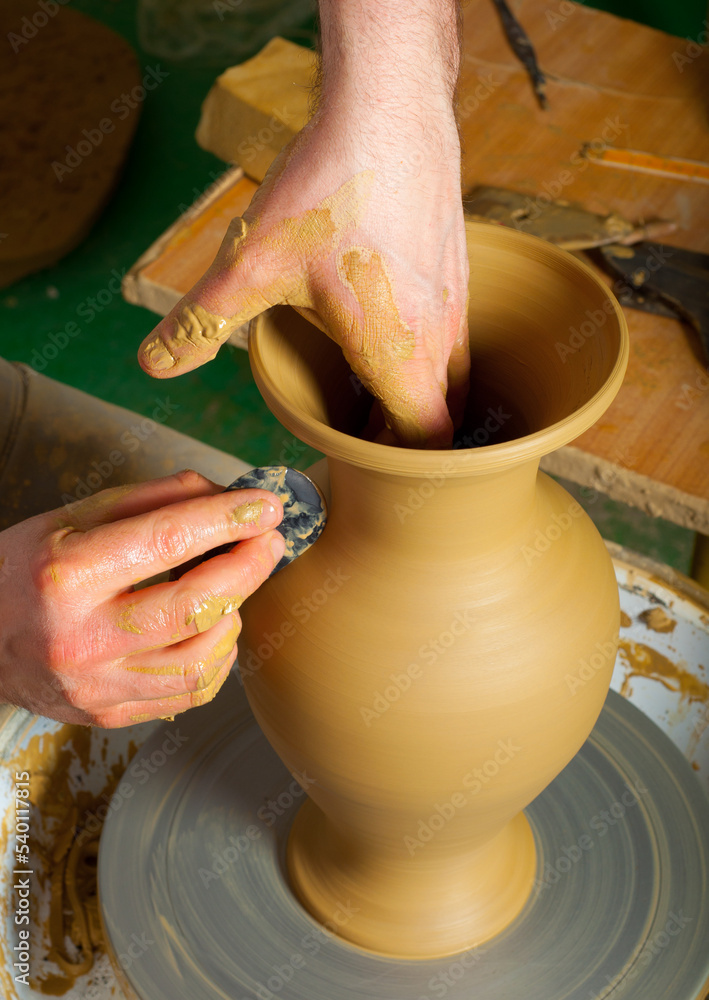 Man professional potter making pottery in his pottery workshop