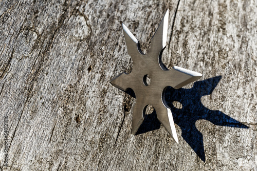 Shuriken (throwing star), traditional japanese ninja cold weapon stuck in wooden background,Silver shuriken with star shape.Samurai, throwing weapons
