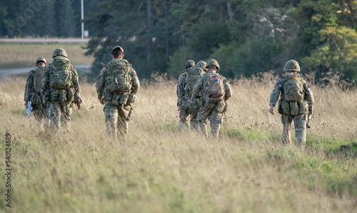 8 British army soldiers tabbing with 25Kg bergens across open countryside