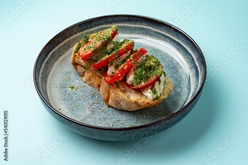 bruschetta with tomato mozzarella and pesto on a plate on a colored background