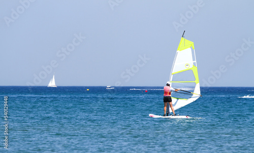 Riding on a board with a sail on the water.Active sea sports in summer.Sailing.