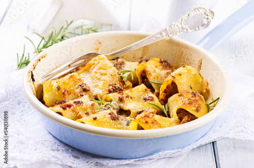 Traditional Italian paccheri pasta filled with minced meat and served with parmesan as close-up in a design pan