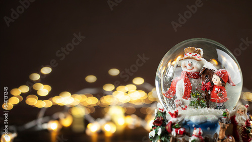 Close up of Christmas snow globe with snowman with defocused bokeh.