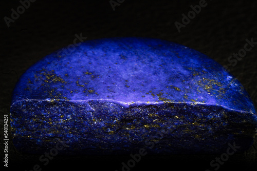 Polished deep blue Lapis lazuli rock macro isolated on black background. 
Dark blue Lapis lazuli with gold Pyrite spots.
Blue rock with gold details