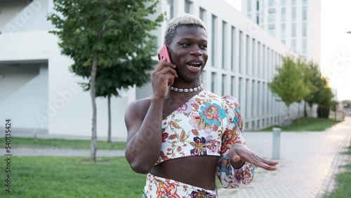 Black gay person in feminine clothes speaking on smartphone photo