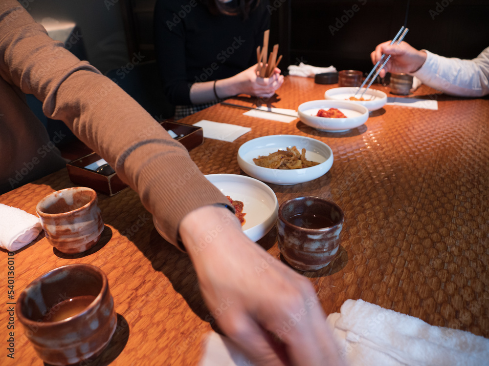 Hands picking at side dishes in a Korean restaurant
