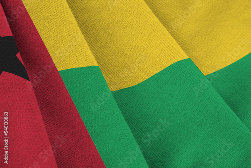 Guinea Bissau flag with big folds waving close up under the studio light indoors. The official symbols and colors in banner photo